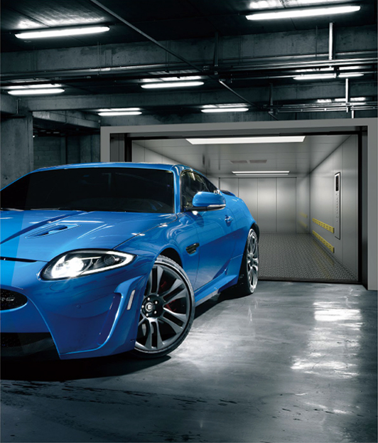 A blue sports car is coming out from a car elevator in a garage.